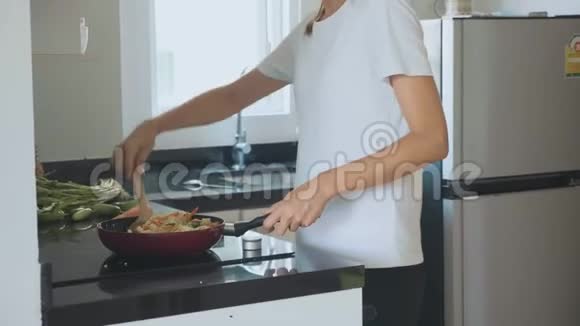 年轻女子在家庭厨房做饭时跳舞唱歌视频的预览图