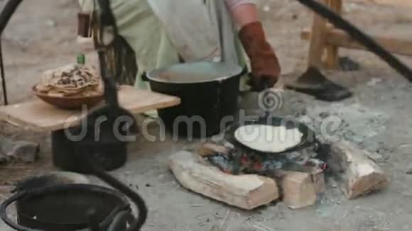 穿中世纪服装的女人坐在火炉旁吃炸煎饼视频的预览图