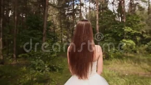 华丽时尚的新娘穿着复古的白色连衣裙走在森林里后景视频的预览图