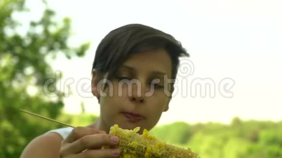 美丽的黑发女孩吃玉米视频的预览图