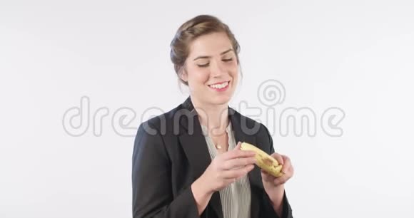 女人在白色的工作室背景上吃黄色香蕉视频的预览图