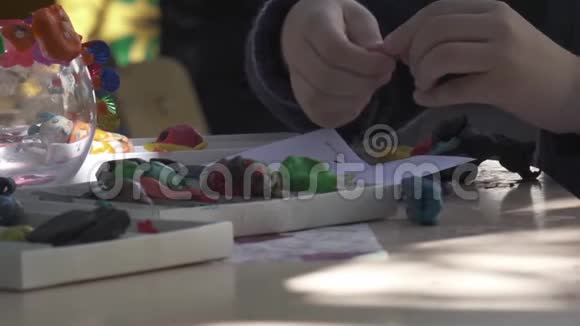 男孩的手臂在家里的桌子上用橡皮泥雕刻人像视频的预览图