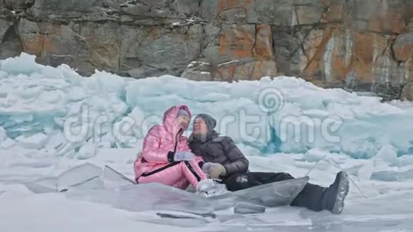 在冰封的湖面上年轻夫妇在冬天散步时玩得很开心恋人们坐在冰上亲吻和拥抱青年视频的预览图