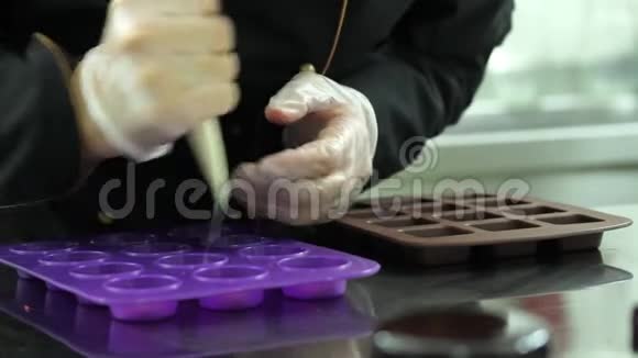 用融化的白巧克力填充硅饼模具的糖果以制作蛋糕装饰品视频的预览图
