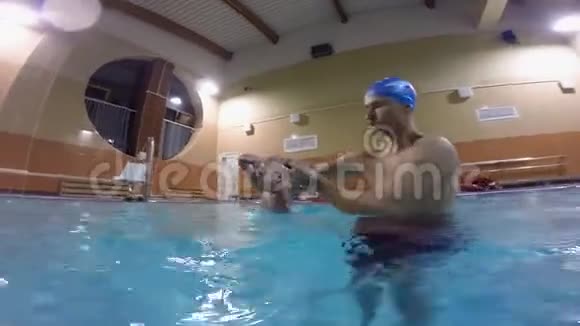 带着孩子在游泳池里的年轻父亲在游泳池里游泳对婴儿进行的复杂的锻炼视频的预览图