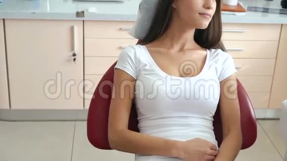 漂亮的女性病人坐在牙科椅上微笑慢动作视频的预览图