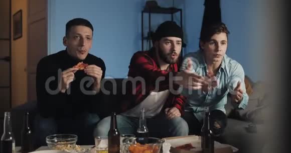 三个朋友在家看电视上的足球赛为最好的足球队加油感情男性球迷庆祝胜利视频的预览图
