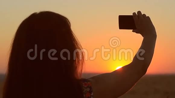 日落时分少女在手机上拍照少女逆天剪影视频的预览图
