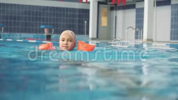 一个穿着充气臂的小女孩漂浮在游泳池里游泳用的橡皮擦这个女孩学游泳视频的预览图