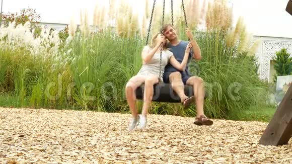 浪漫的夫妇年轻的女人和男人在秋千上摆动吊床在城市的游乐园4k复制空间视频的预览图