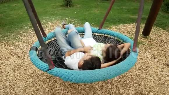 男孩和女孩双胞胎在城里游乐园的吊床上荡秋千4k复制空间视频的预览图
