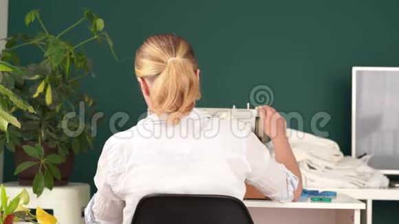 在家工作年轻的金发女人在明亮的房间里用打字机缝衣服视频的预览图