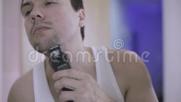 年轻人在浴室里用电动剃须刀刮胡子视频的预览图
