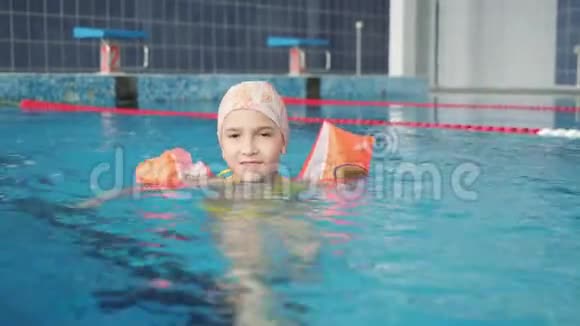 一个穿着充气臂的小女孩漂浮在游泳池里游泳用的橡皮擦这个女孩学游泳视频的预览图