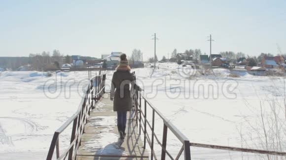 阳光明媚的冬日在农村女人穿过一座桥视频的预览图