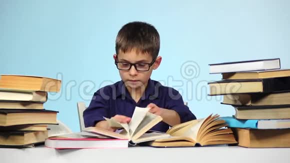 小男孩在读另一本书蓝色背景慢动作视频的预览图