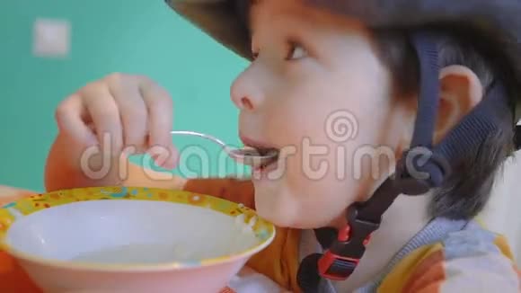 戴运动头盔的可爱男孩在骑马前吃粥视频的预览图