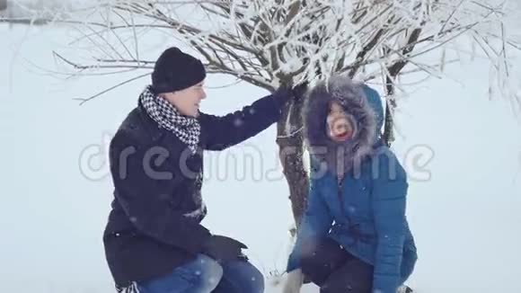 那家伙和那个女孩正在把雪从树上刷下来视频的预览图