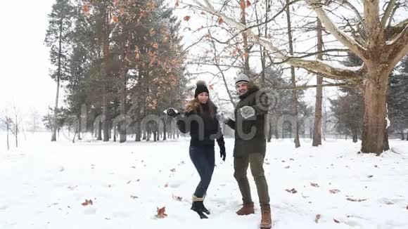 在童话般的冬天天气里一对相爱的夫妇玩雪球慢动作视频的预览图