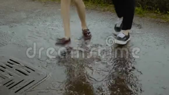 女性和男性的双脚跳舞跳在下水道的雨水池里视频的预览图