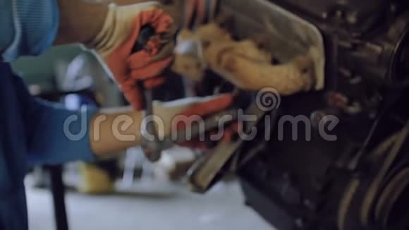 有胡子的机械师用悬挂在修理车间的汽车马达外壳上的工具紧固螺栓视频的预览图