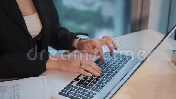 年轻的女商人坐在摩天大楼的一层高的窗户旁在笔记本电脑上工作视频的预览图
