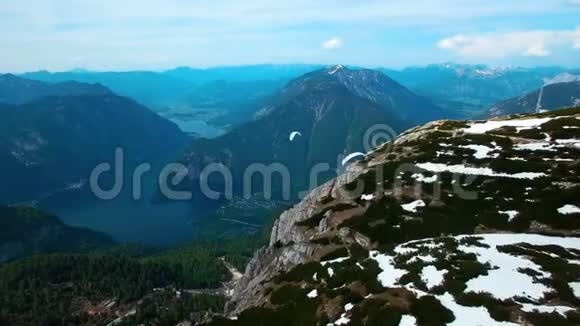 从奥地利雪山起飞的白色降落伞飞行滑翔伞的空中全景视频的预览图
