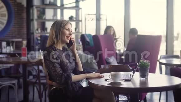 快乐的年轻女人在咖啡店里打电话和使用电脑一个美丽的女孩情感交流视频的预览图
