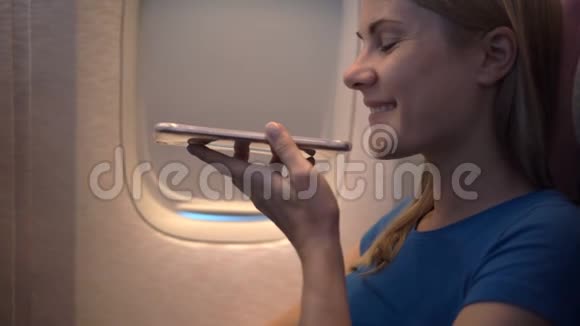 飞机窗户附近美丽迷人的女人长途飞行在她的智能手机上聊天视频的预览图