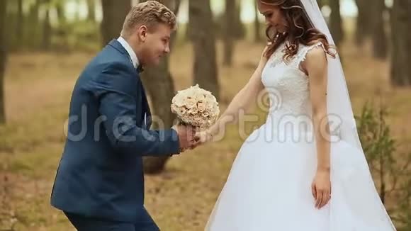 新郎给新娘一束她单膝站在大自然上的花快乐的新郎托起新娘围着她转视频的预览图