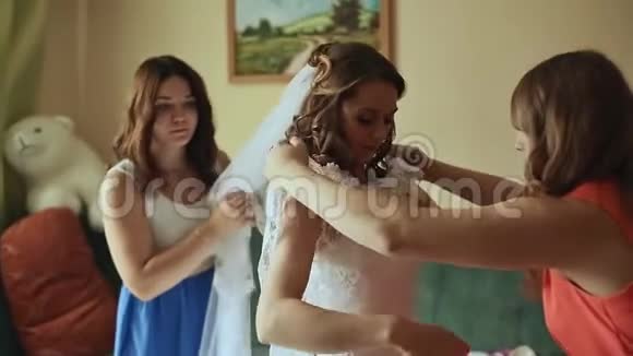 美丽的伴娘帮助快乐的新娘穿好衣服视频的预览图