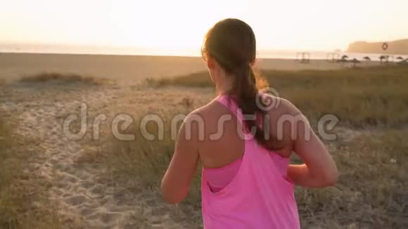 运动的女人沿着海滩奔向海洋慢动作视频的预览图