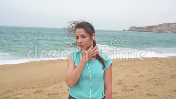 海滩上的女人用智能手机耳机听音乐拿撒勒葡萄牙慢动作视频的预览图