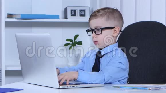聪明的男孩正在笔记本电脑上打字它自己写在叶子上视频的预览图