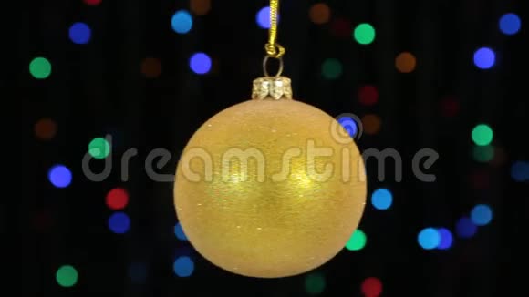 黄色圣诞球摆动在离焦背景与闪烁的花环灯视频的预览图