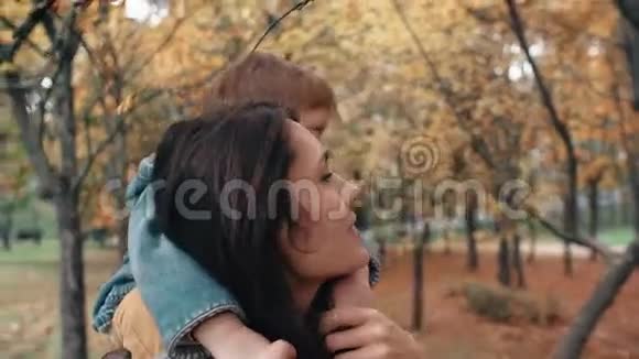 年轻的妈妈抱着可爱的小男孩小男孩抱着她在令人惊奇的秋天公园4k附近的喂鸟者视频的预览图