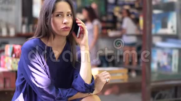 年轻的黑发女孩在街头咖啡馆用手机聊天视频的预览图