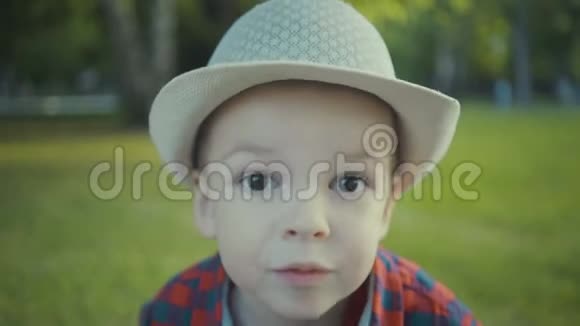 公园里一个两岁的男孩戴着帽子和衬衫的肖像视频的预览图