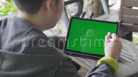 男孩在平板电脑上看绿色屏幕色度键视频的预览图