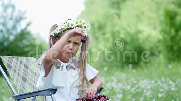 肖像金发女孩孩子坐在雏菊中间在草地上她的头发用雏菊装饰她微笑而且视频的预览图