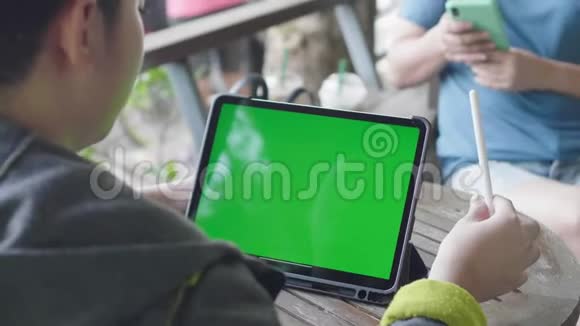 男孩在平板电脑上看绿色屏幕色度键视频的预览图