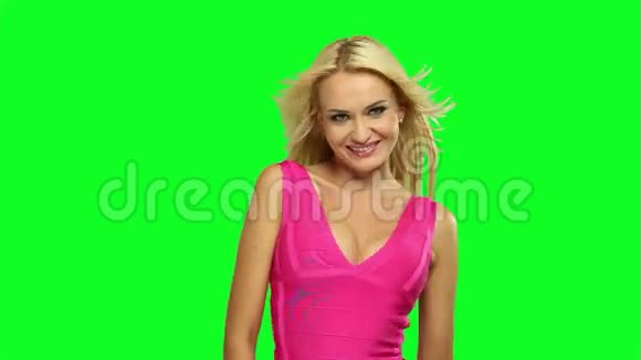 漂亮的白种人金发女人穿着粉红色的裙子在荧光绿色的背景下跳舞视频的预览图
