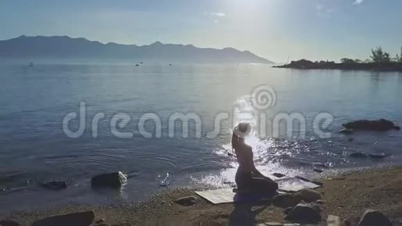 从瑜伽中的女式剪影到日出时的海洋视频的预览图