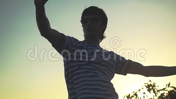 在惊人的日落舞蹈中的自由男人用手机在山顶慢动作自拍视频的预览图