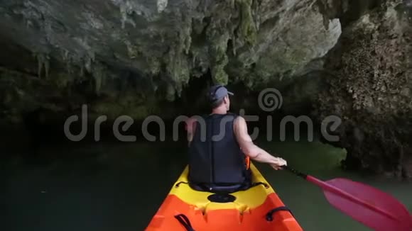 年长强壮的人在黑暗洞窟中沿河划船视频的预览图