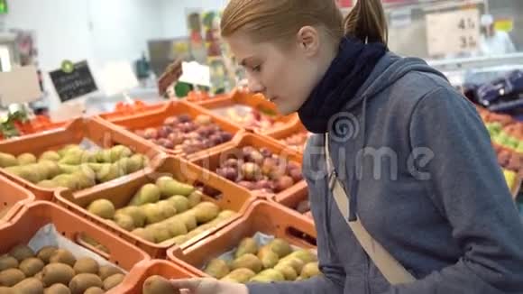 美丽迷人的年轻女人在超市挑选猕猴桃水果健康的饮食观念视频的预览图
