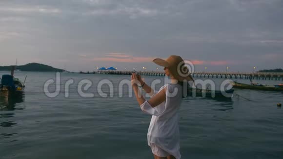 美丽的女人在天堂海滩用智能手机拍照视频的预览图