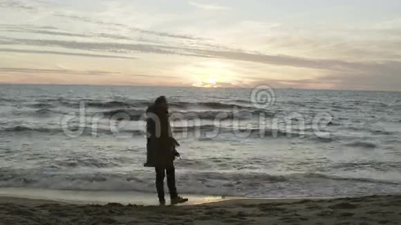 年轻人扔沙子跑到海边悲伤的雄性在海滩上享受日落和波浪在刮风的日子视频的预览图