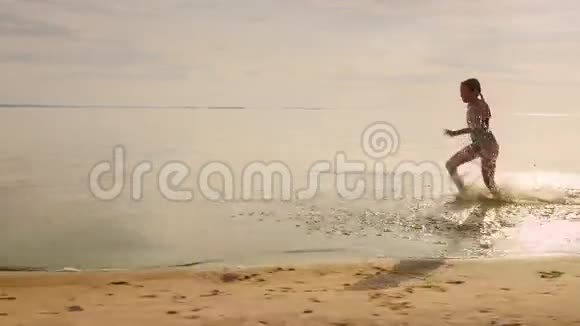 无忧无虑的7岁女孩在水里奔跑从她的脚上飞起许多飞溅视频的预览图