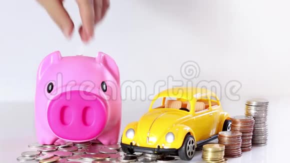 手把一枚硬币和一辆玩具汽车放进储蓄罐视频的预览图